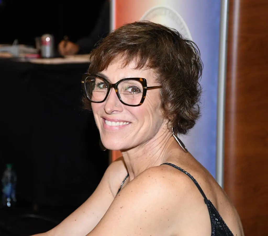 A woman with glasses smiling for the camera.