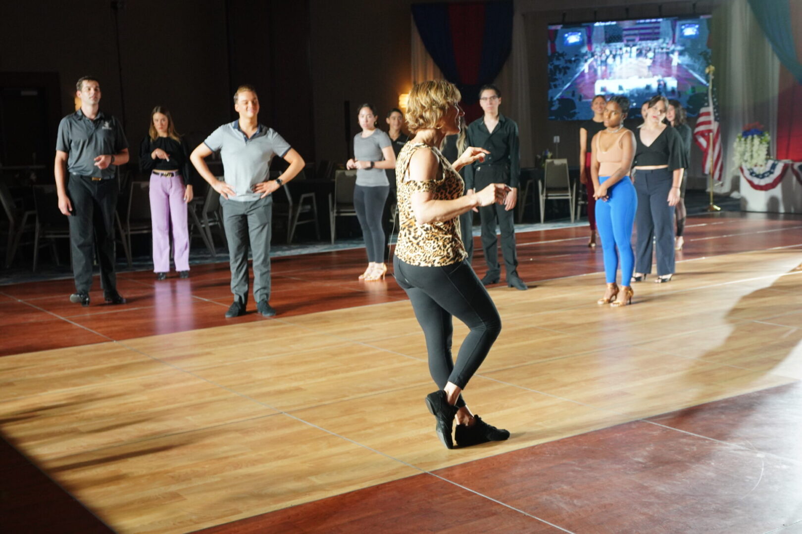 A woman in black pants and leopard print shirt dancing.
