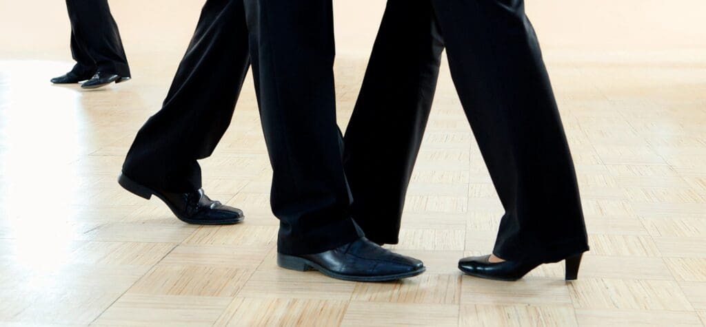 A close up of three people wearing black shoes